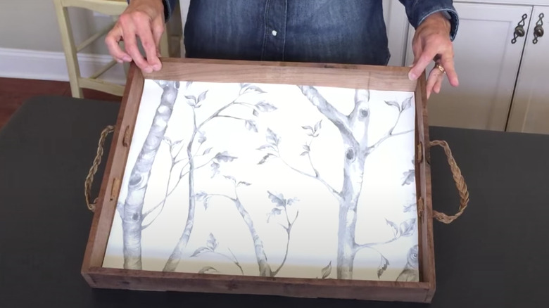 person putting wallpaper on tray