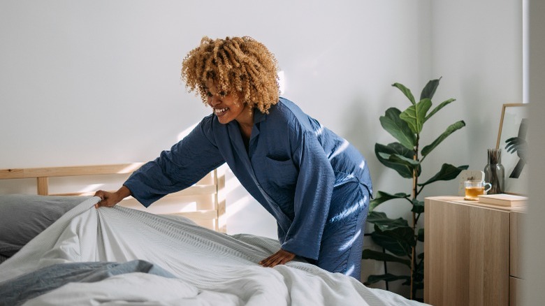 Smiling woman arranging bedsheets