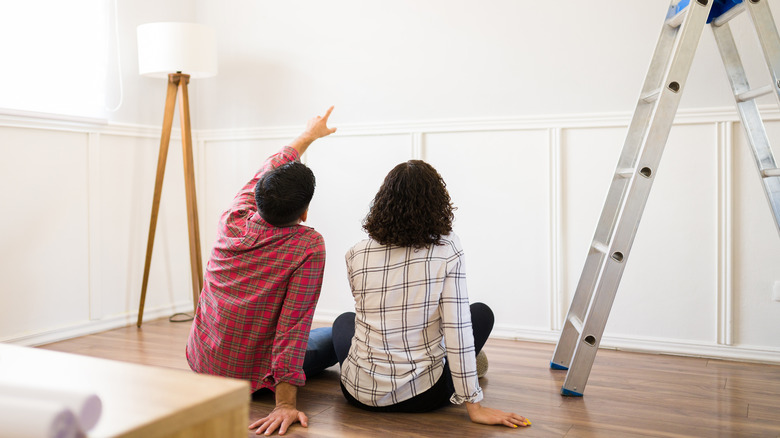 A couple contemplating how they're going to design a wall in their home