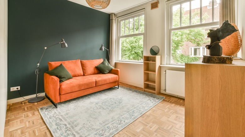 Small living area with green accent wall and orange sofa