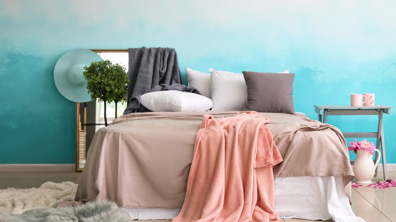 Bed with pink blanket and blue gradient wallpaper