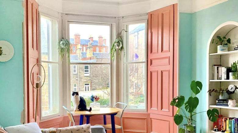 Restored pink traditional wooden shutters designed to cover a bay window from the inside