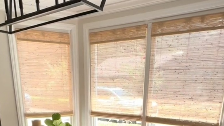 Bamboo woven blinds grace the bay window of a stylish dining room