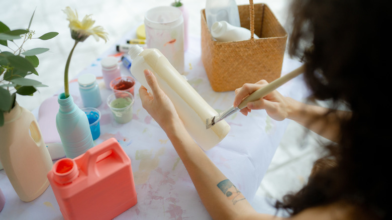 woman painting bottle vase