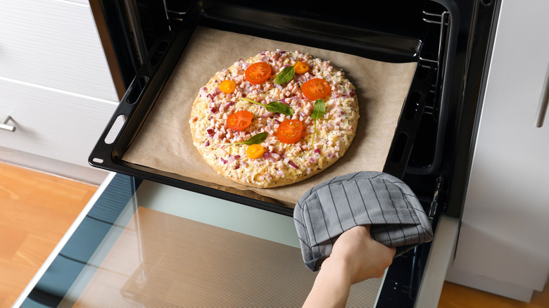 woman putting pizza in oven