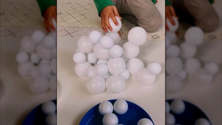 Child making sculpture out of ping pong balls