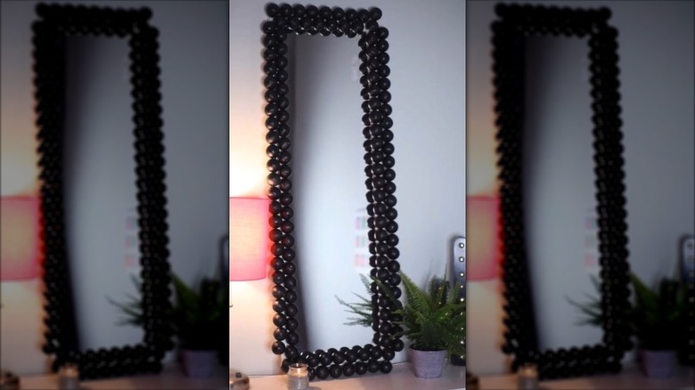 Standing mirror frame decorated with black ping pong balls