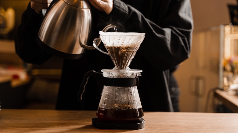 person using pour-over coffee maker