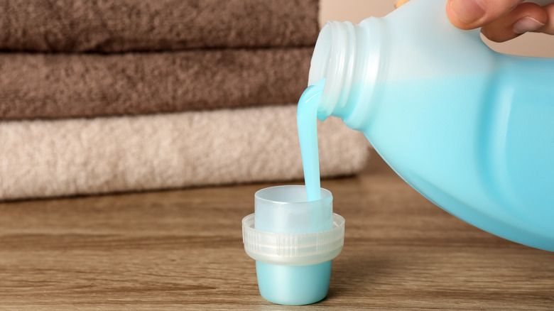 person filling cap with fabric softener