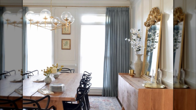 Blue pinch-pleat curtains hung in a farmhouse dining room