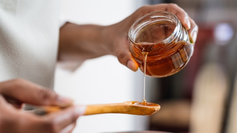 pouring honey onto wooden spoon