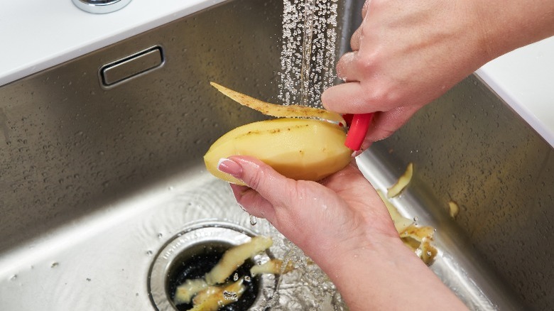 peeling potato in sink