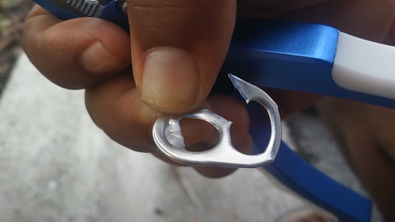 Fingers holding soda can tab hook