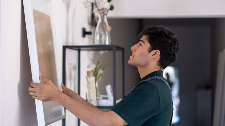 man hanging picture frame