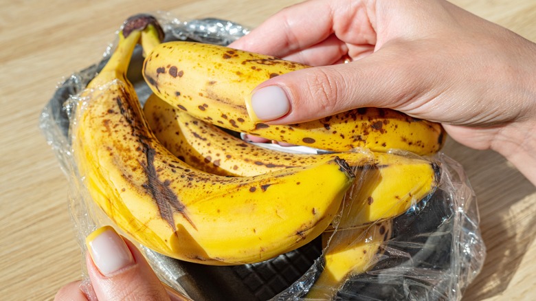 Hands holding spotted brown bananas