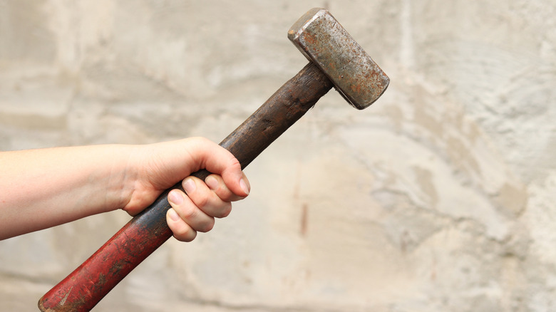 Person holding a sledgehammer against a blurry background