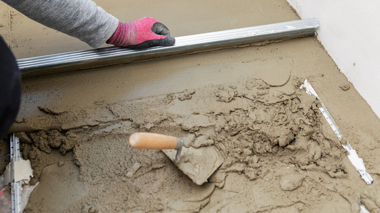 Worker using screed board guided by screed rail