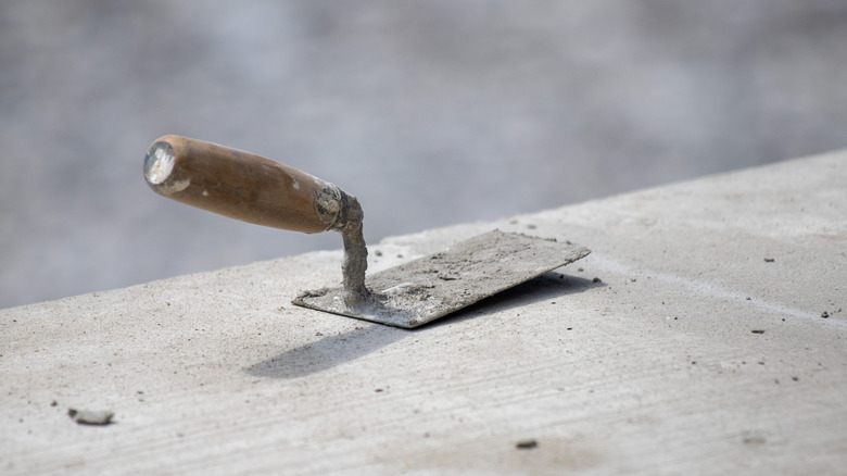 A square-edged trowel placed on a concrete surface