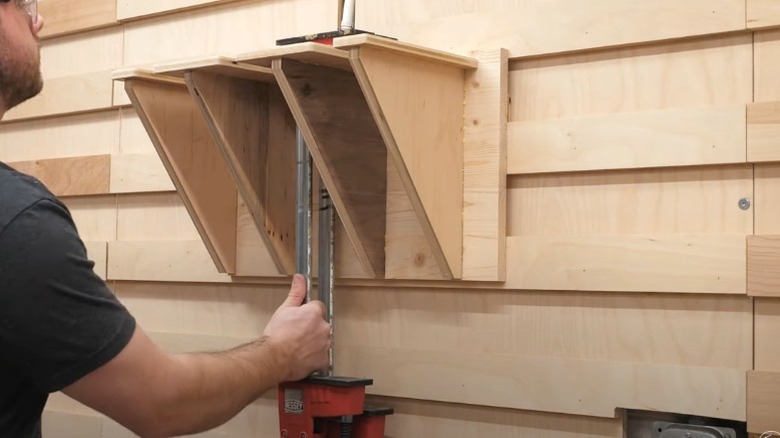 man putting large clamp on French cleat wall