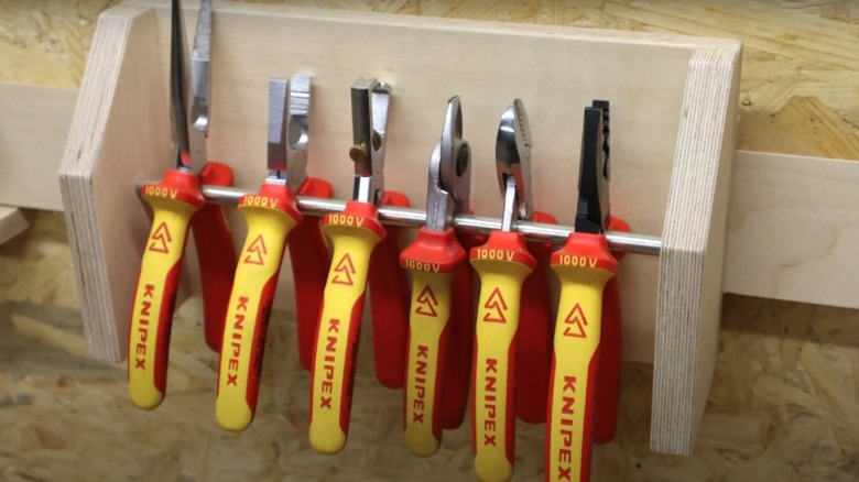 yellow and red-handled pliers hanging on cleat wall rack