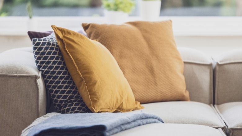 Gold, brown, and black toss pillows on beige sofa