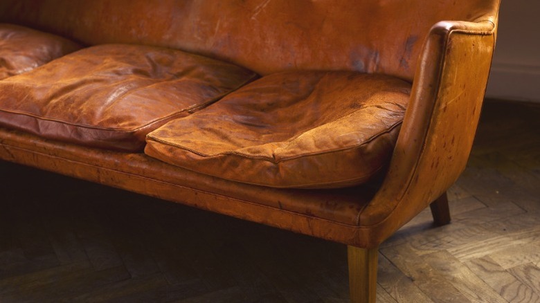 Worn brown leather sofa with collapsed seat cushions