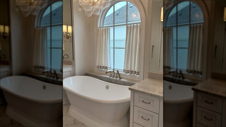 White half curtains hung in an arched window in a bathroom