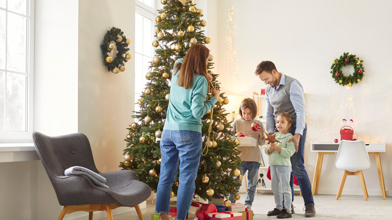 A family decorating a Christmas tree inside their home