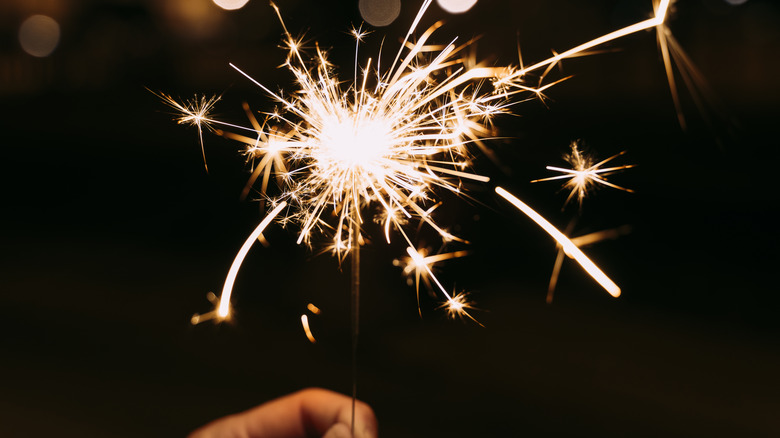 A hand holding a burning sparkler