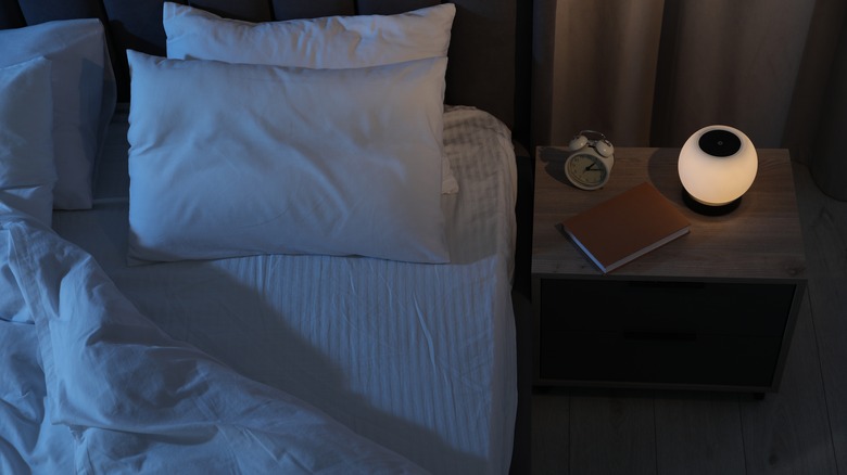 Book and alarm clock on bedside table