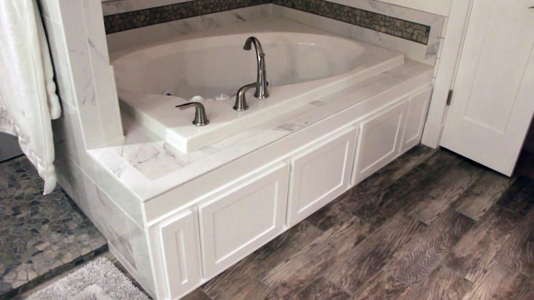 marble bathtub with white cabinets