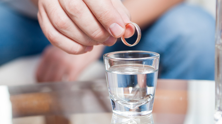 Person holding ring over vodka glass