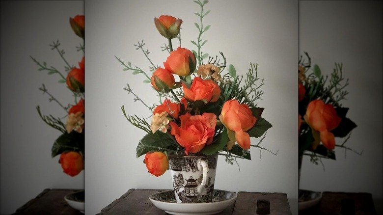 orange roses in teacup vase