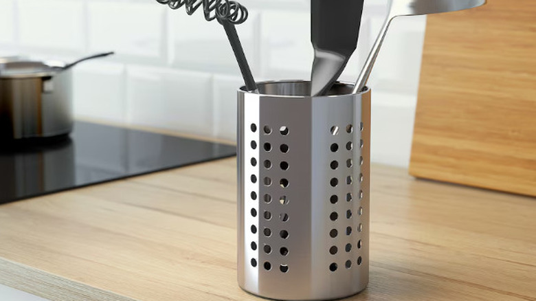 A stainless steel utensil holder in a kitchen