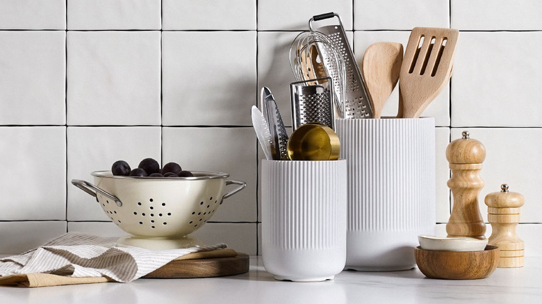 Wooden and metal kitchen utensils are neatly organized into two white containers