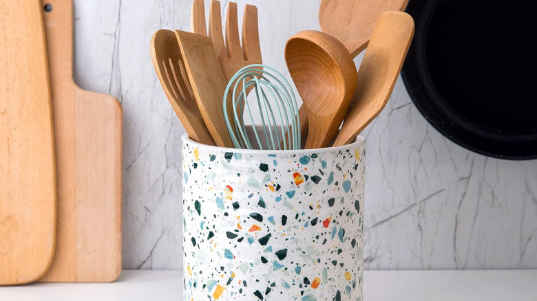 A blue and orange flecked terrazzo utensil holder sits on a white countertop