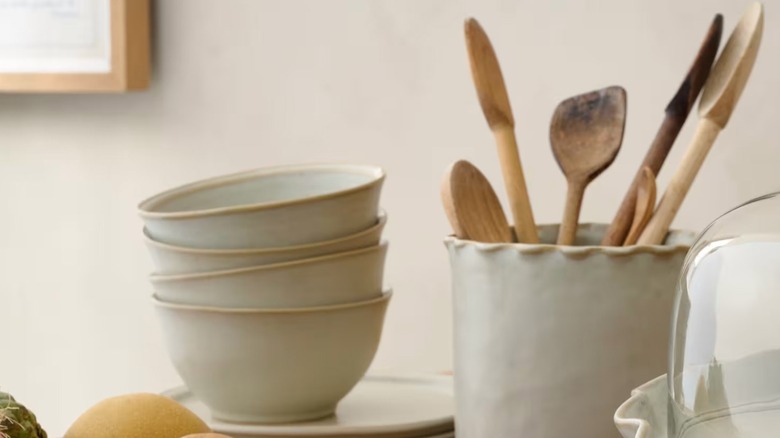 A French gray ceramic utensil holder sits next to a stack of dishes