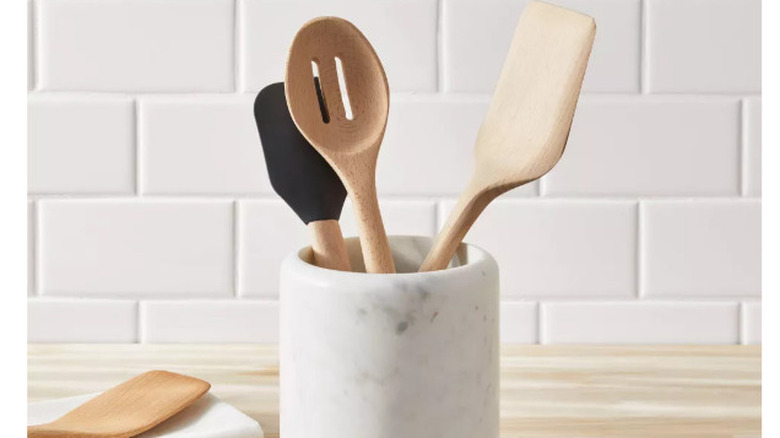 A small marble utensil holder sits on a wooden countertop