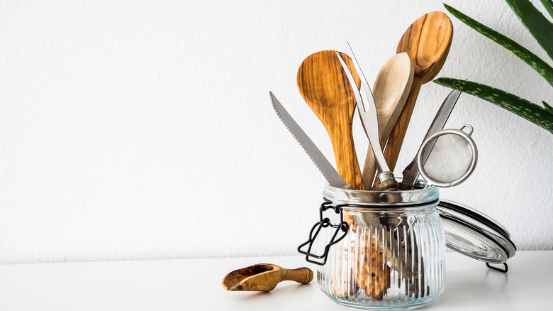 Assorted utensils and cutlery sit in a mason jar