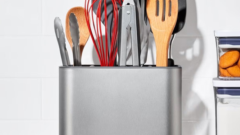 A stainless steel OXO utensil holder sits on a countertop