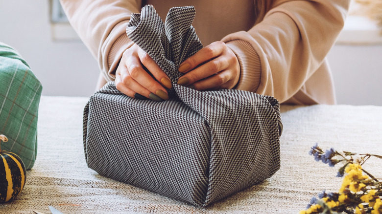 person wrapping gift with cloth