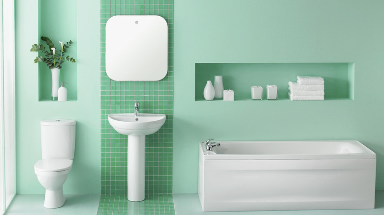 Mint green bathroom wall with sink, tub, and toilet