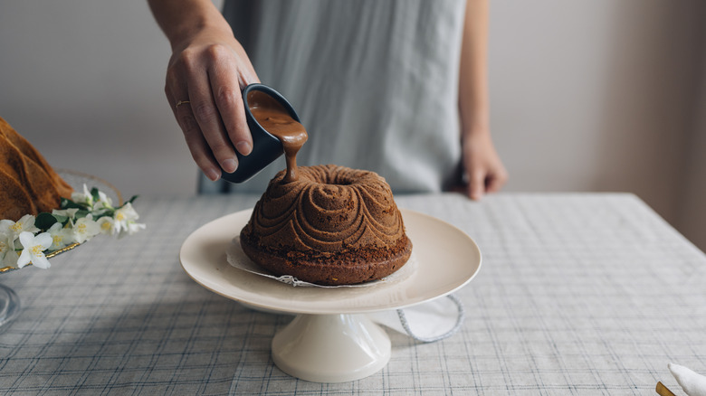 man icing cake on cake stand