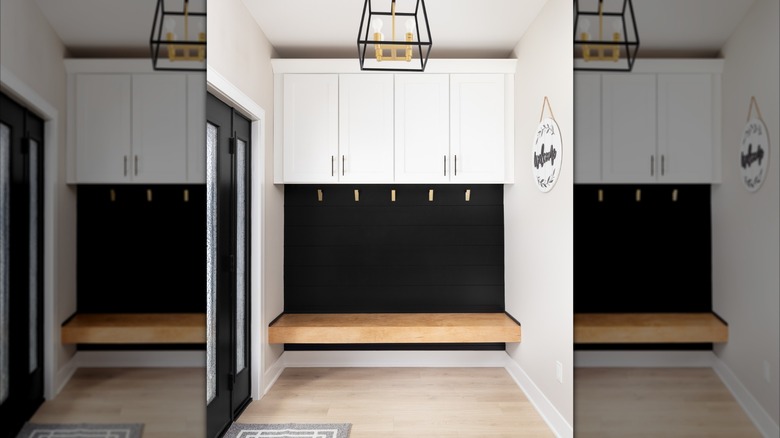 Black entryway accent wall with cabinets and a wood bench