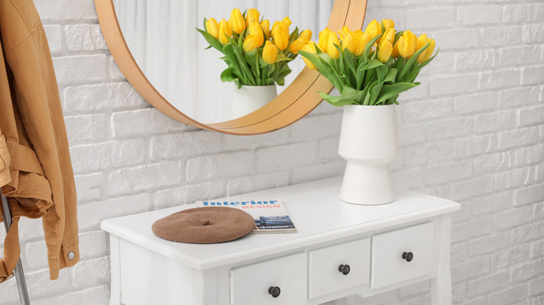 White brick wall in entryway with wooden mirror