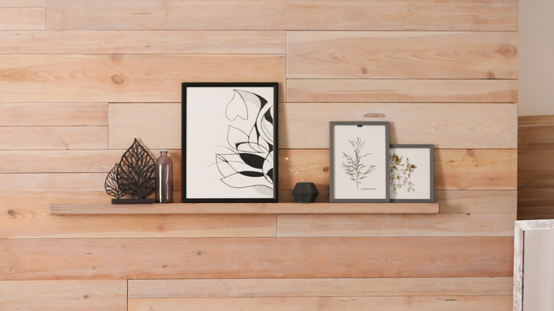 Floating shelf on wooden wall with frames