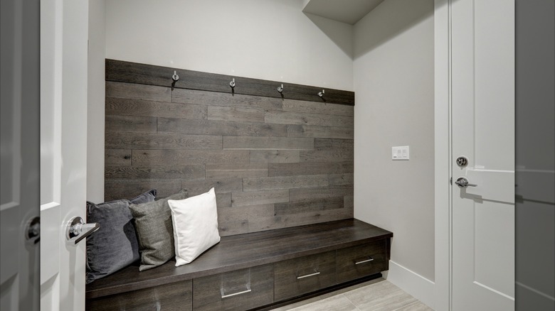 Gray accent wall paneling with hooks and drawers in entryway