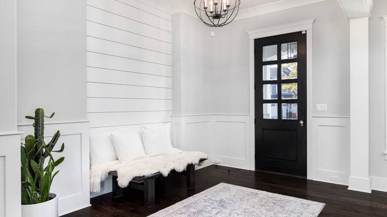 White shiplap wall in entryway of home with black door