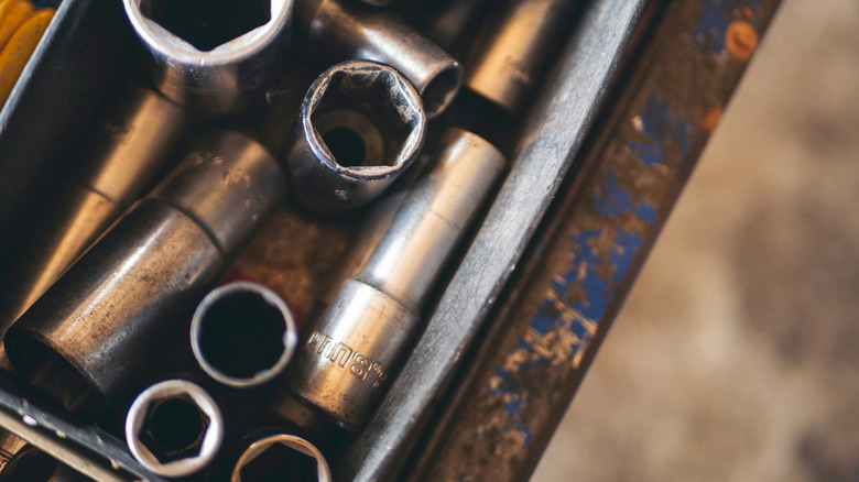 A top view of tarnishing lug nuts in a rusted tool box.