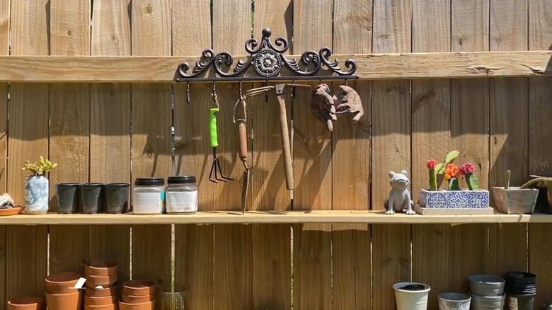 An old metal rack being used for hanging gardening tools